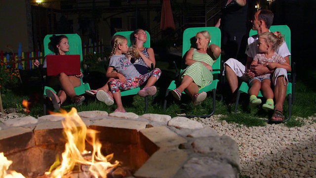 黄昏时分，一家人坐在后院的露台上，靠近燃烧的火坑视频素材