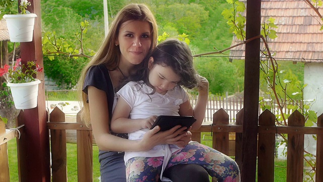 母亲和女儿使用平板电脑视频下载