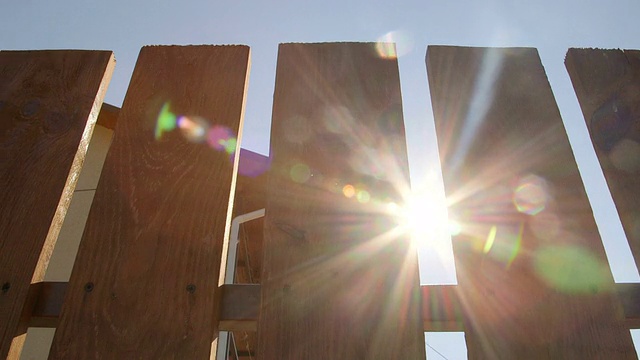 阳光透过一个新的木栅栏在后院拍摄小车视频素材