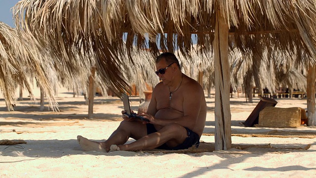 在海滩上用笔记本电脑放松视频素材