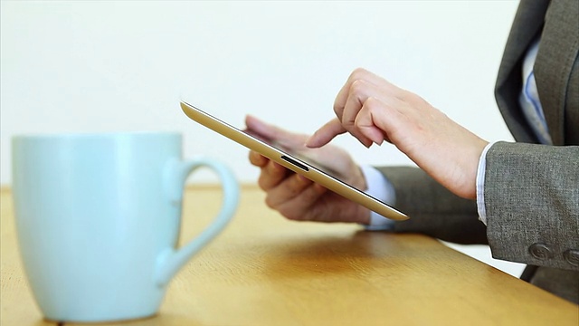 女商人在喝咖啡的时候使用平板电脑视频下载