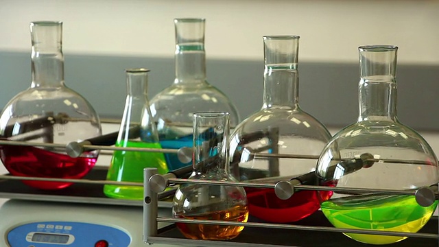 实验室玻璃器皿装满了颜色溶液，在两个摇瓶上旋转视频下载