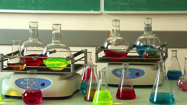 实验室玻璃器皿与颜色溶液同步旋转在两个摇瓶和一些烧瓶周围视频下载