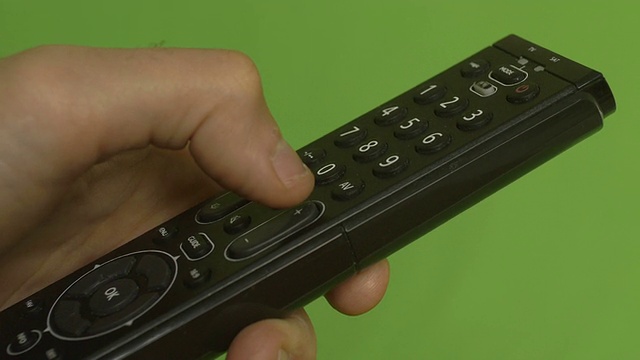 男性的手在绿色屏幕上用遥控器换频道。视频下载