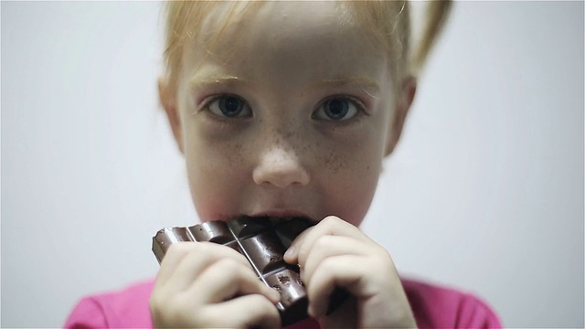 小女孩吃巧克力孤立在灰色背景视频素材