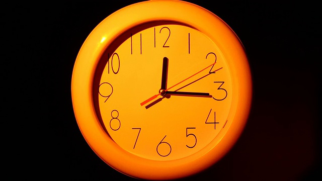 橙色时钟与阴影在黑色背景上的图标，夜晚视频素材