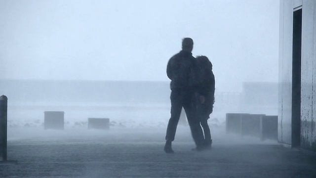 在冰岛雷克雅未克的暴风雪中，一名男子和一名女子站在建筑外视频素材