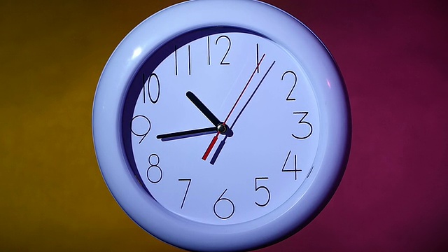 彩色背景上的一个白色时钟的特写。慢动作视频素材