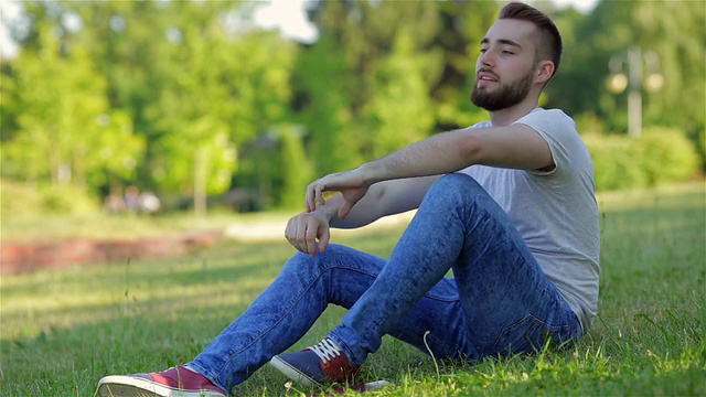 一个年轻人坐在公园里看他的日记视频下载