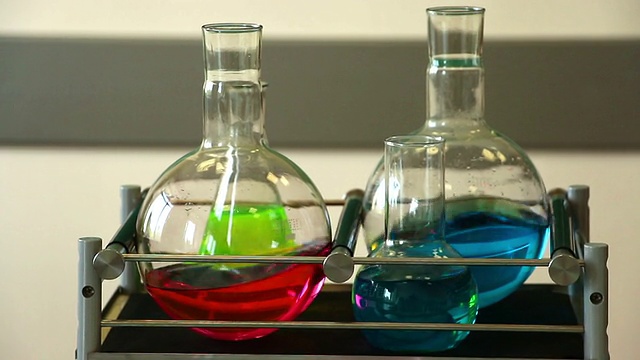 四个玻璃器皿与彩色溶液搅拌在实验室摇床上视频下载
