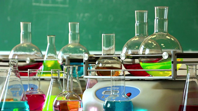 实验室玻璃器皿与彩色液体旋转在两个摇瓶和一些烧瓶周围视频下载
