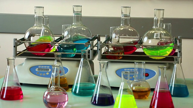 实验室玻璃器皿的颜色溶液在两个摇瓶上旋转，一些烧瓶放在前面视频下载
