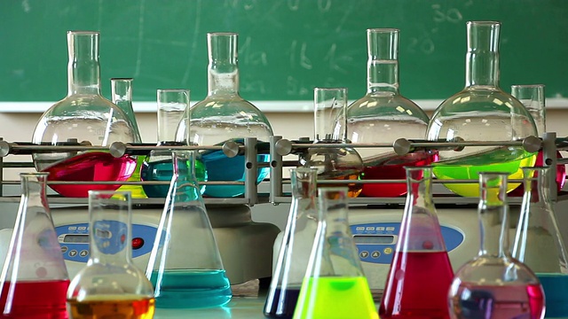 实验室玻璃器皿与颜色溶液同步旋转在两个摇瓶和一些烧瓶在前面视频下载