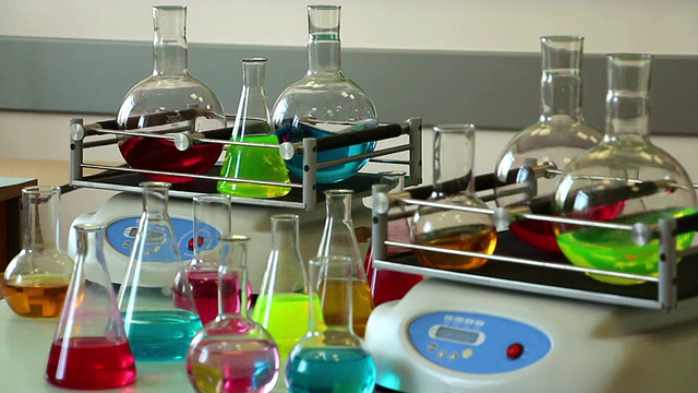 五颜六色的实验室玻璃器皿在摇瓶和桌子上集中在背面视频下载