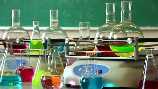 实验室玻璃器皿与彩色液体旋转在两个摇瓶和一些烧瓶周围的另一个角度视频下载