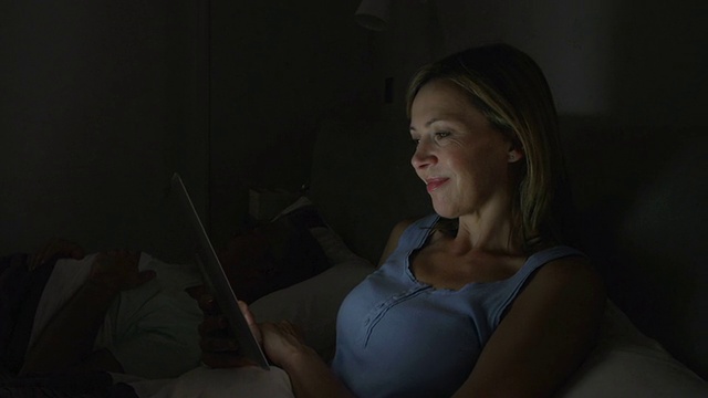 中年夫妇在床上与使用平板电脑的女人视频素材