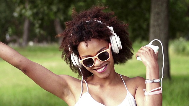 非洲裔美国年轻女子戴着耳机听音乐视频素材