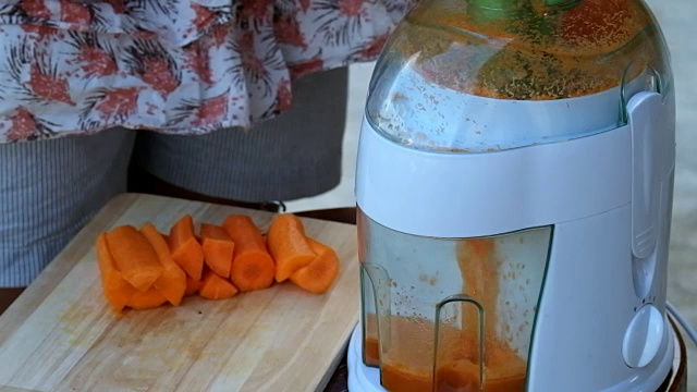 现代电动搅拌机用胡萝卜榨汁。生的胡萝卜汁视频素材