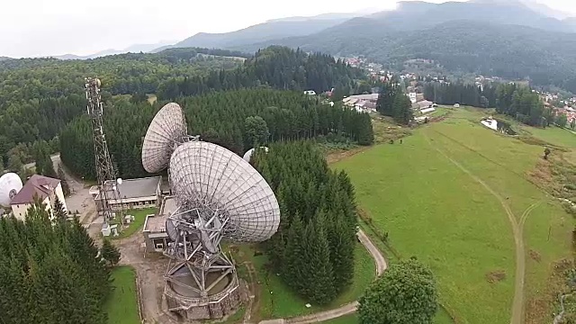 大型碟形卫星天线阵列接收和广播山区景观，鸟瞰图数据信号视频素材