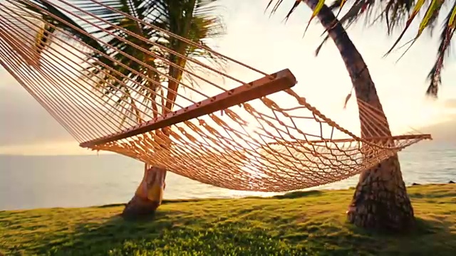 吊床和棕榈树在日落美丽的太阳耀斑视频素材