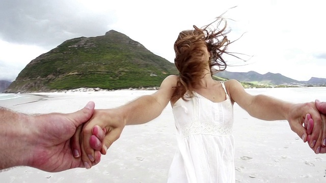 一对情侣在海滩上手牵手的裁剪图像视频素材