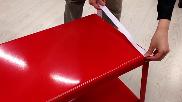 一个女人在宜家店里测量红色桌子的尺寸视频素材