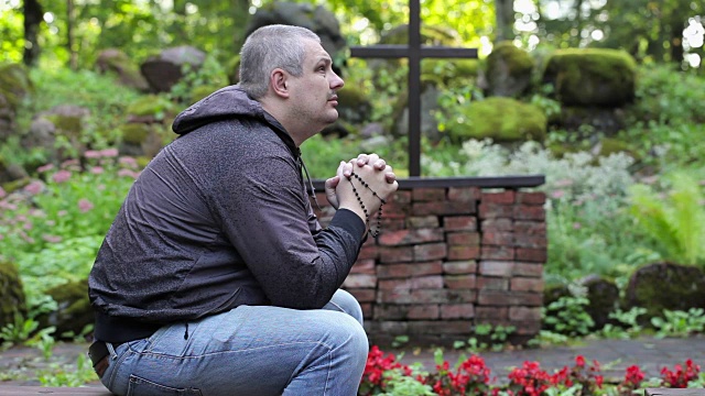 男人在长凳上祈祷与念珠在户外教堂视频下载