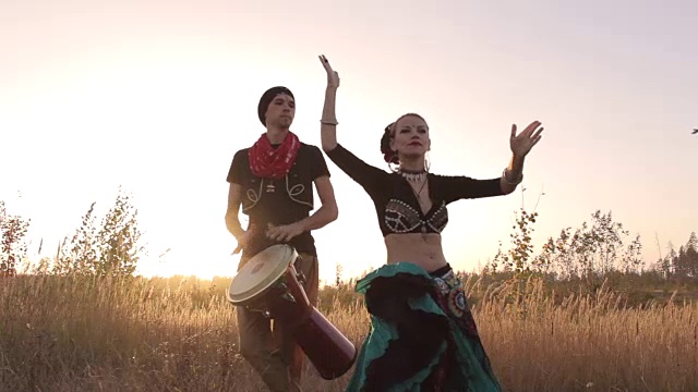 美丽的女孩和鼓手跳着异国情调的舞蹈视频素材