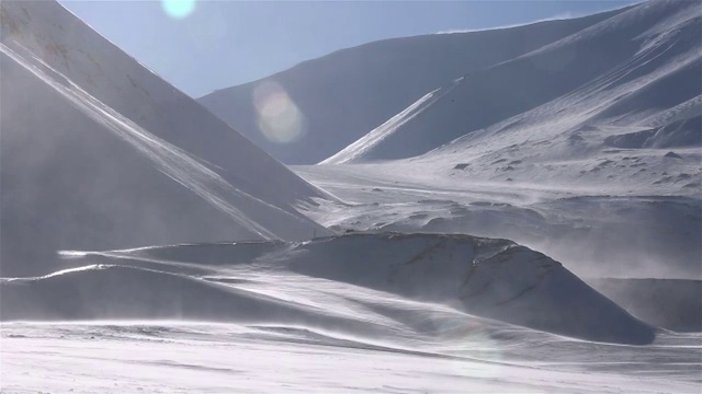 一个孤独的旅行者正穿过暴风雪，背景是雪山。视频素材