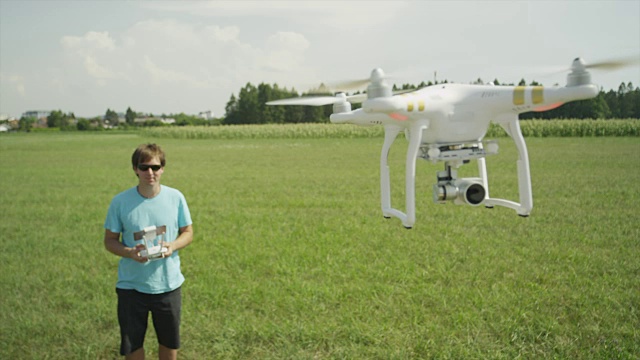 慢镜头:年轻的飞行员在田野上驾驶业余无人机视频素材