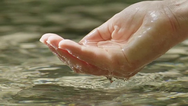 慢镜头特写:女性用手舀出纯净的水视频素材