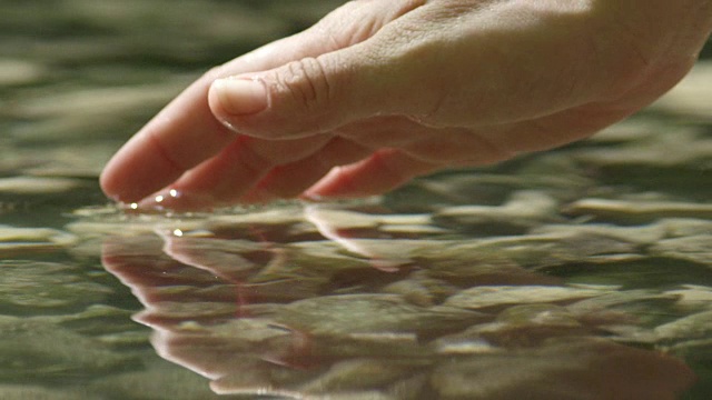 慢动作特写:手抓住和举起水晶清澈的水视频素材