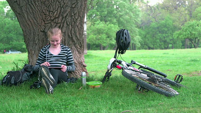 女孩在公园里用数码平板电脑视频下载