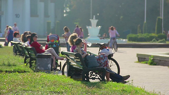 人们坐在长椅上，在炎热的天气里喝水。放松视频素材