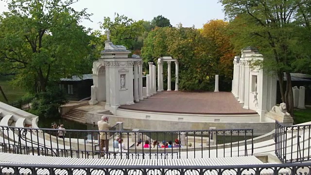 华沙Lazienki公园的旧圆形剧场。一群游客坐下视频下载