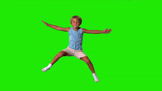 男孩在绿色屏幕上伸开四肢跳跃视频素材
