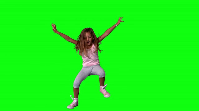 可爱的小女孩在绿色的屏幕上伸开四肢跳跃视频素材