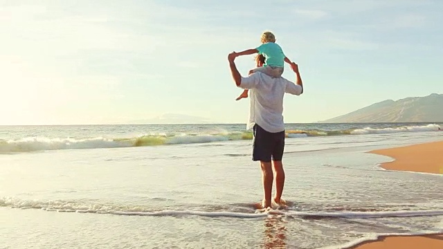 父亲和儿子一起在海滩上玩日落。视频素材