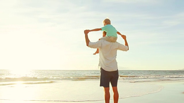 父亲和儿子一起在海滩上玩日落。视频素材