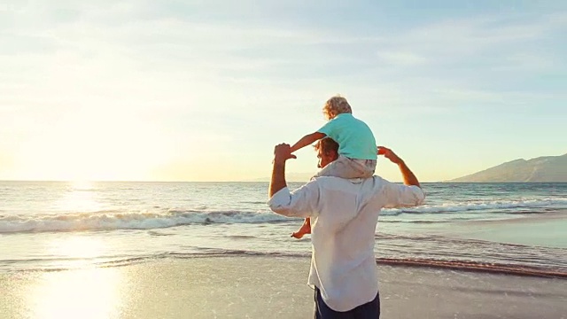 父亲和儿子一起在日落的海滩上玩飞机。视频素材