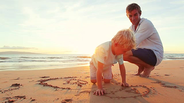 父亲和儿子一起在沙滩上画日落。视频素材