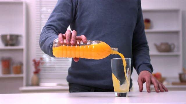 往玻璃杯里倒橙汁的人视频素材