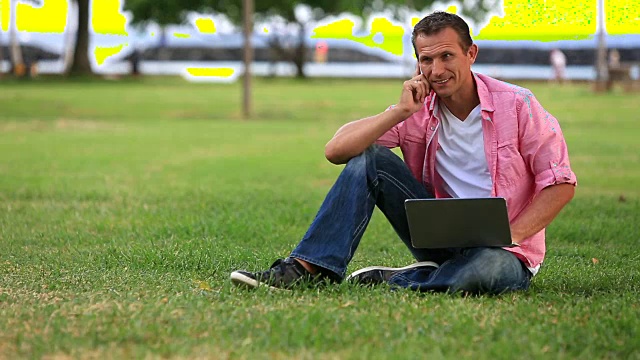 坐在草地上用笔记本电脑的人视频素材
