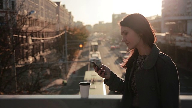 美丽的女孩在一座城市的桥上使用智能手机视频素材