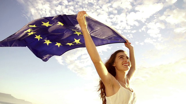欧洲妇女举着欧盟旗帜对抗天空飘扬视频下载