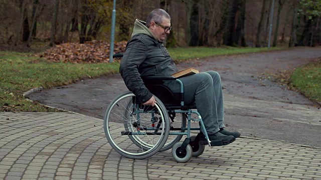 在公园户外的小路上坐轮椅的残疾人视频素材