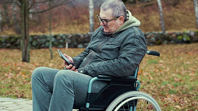 轮椅上使用平板电脑的残疾人视频素材