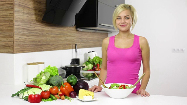 微笑的女人在厨房里搅拌沙拉视频素材