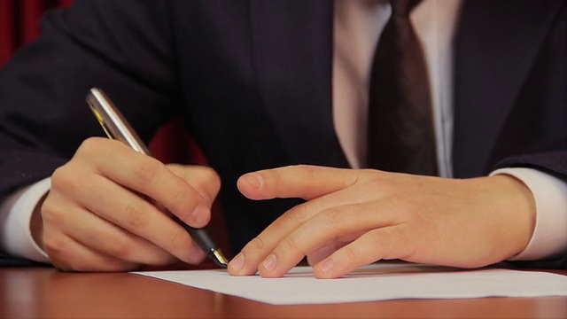 男上司在文件上签字，签署一份协议视频素材