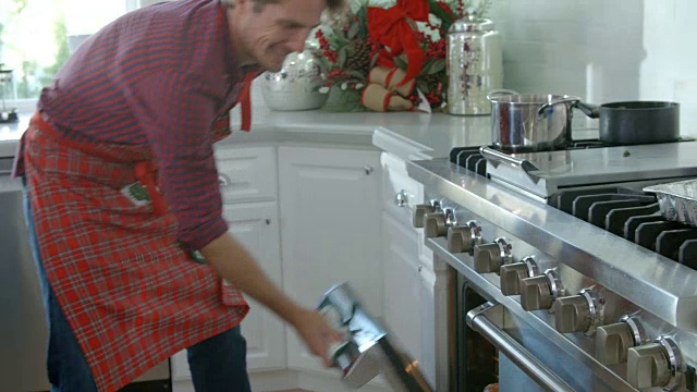 爸爸把圣诞火鸡从烤箱里拿出来的慢动作镜头视频素材